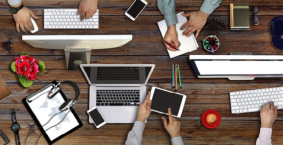 A desk of public selector employees working on laptops in a meeting